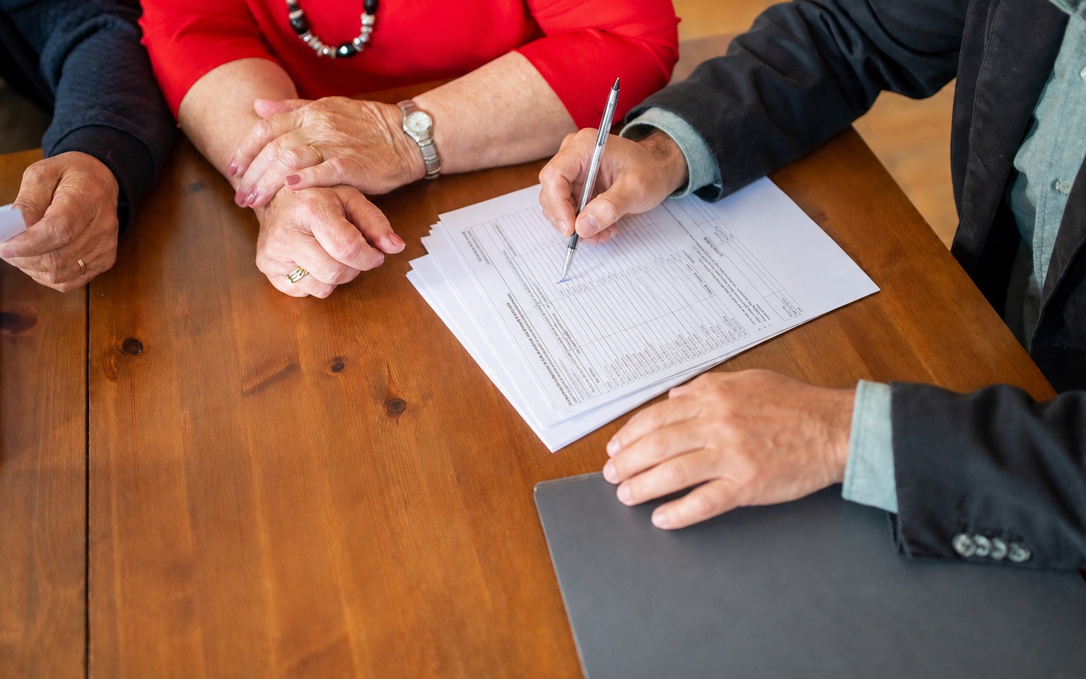 Advisor reviewing a printed commercial loan portfolio worksheet with clients
